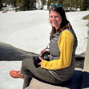 Sarah Bolt, Photographer and Videography sitting and smiling with a camera