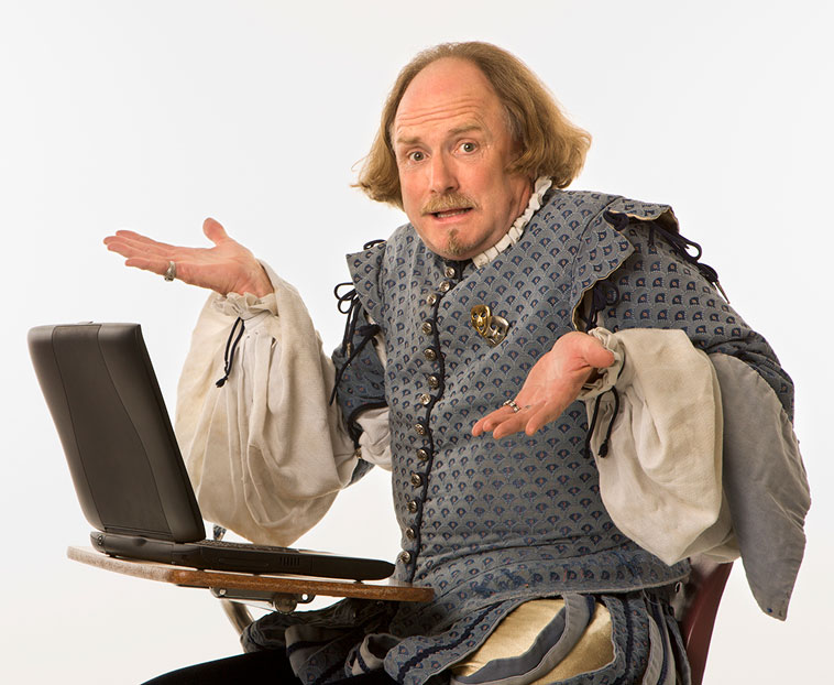 shakespeare Actor in Shakespeare costume sitting confused next to a laptop